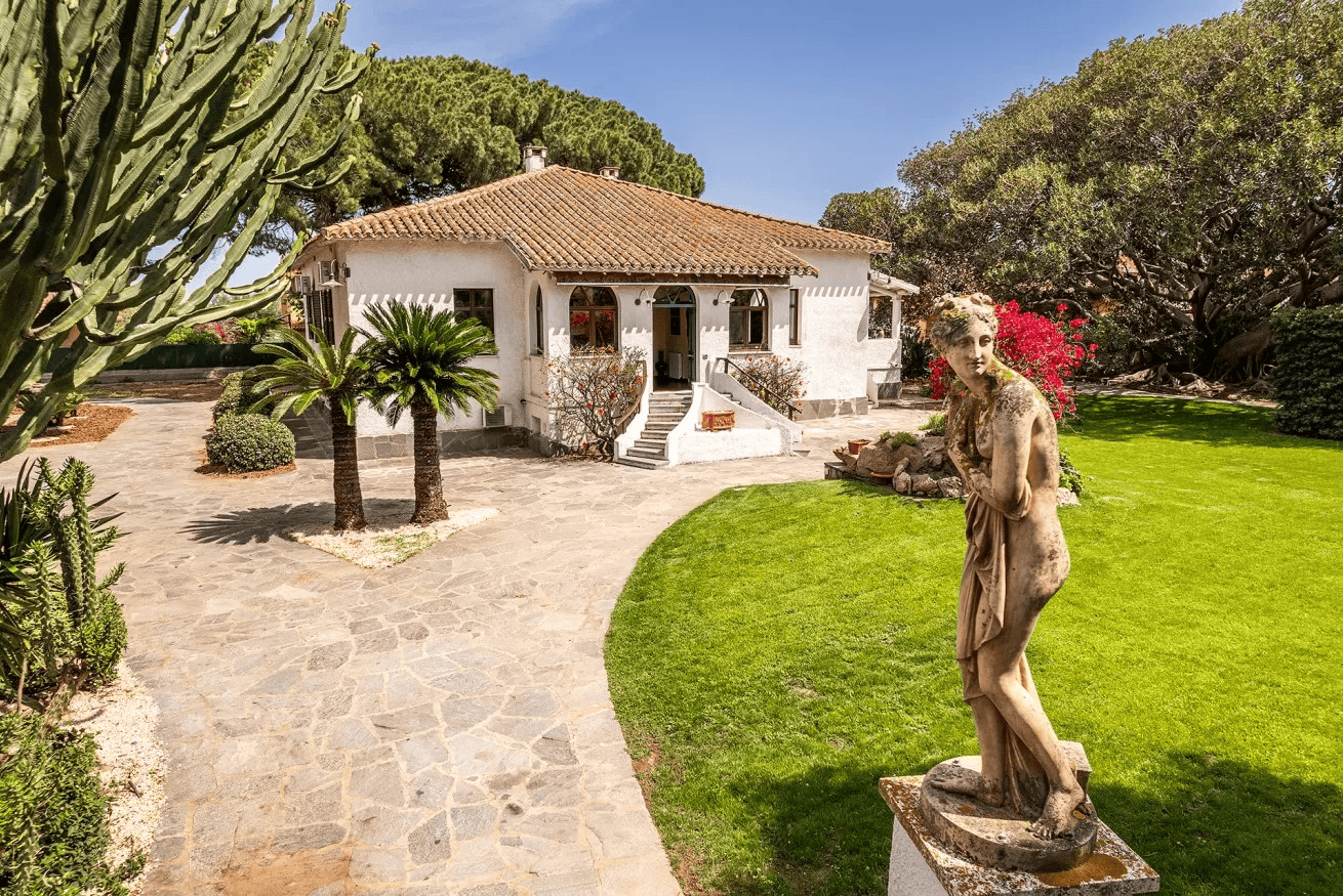 a villa with a garden and a statue in the foreground